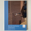 A hardcover book titled 'Architecture Ireland' with a blue spine and lower band, featuring a photograph of a brown brick building facade on the cover. The RIAI logo appears in the bottom right corner.
