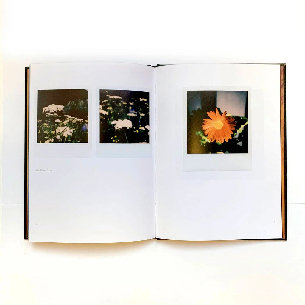 An open book laid flat on a white surface, showing three printed floral photographs spread across the pages.