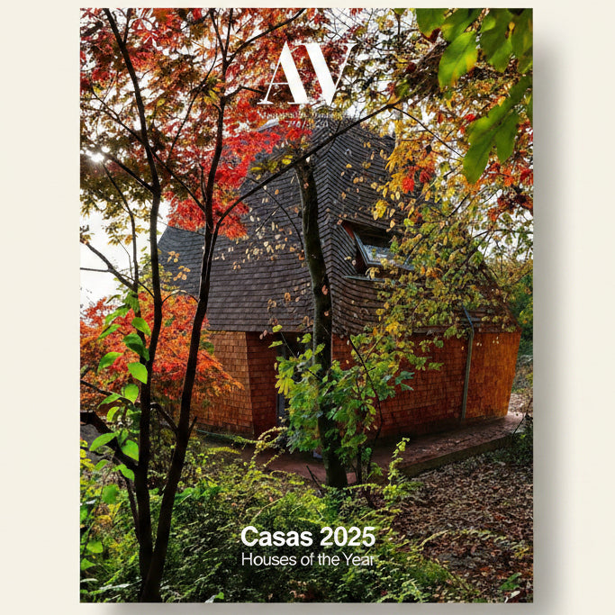 Cover of a magazine featuring a wooden cabin in a forest with autumn foliage, titled 'Casas 2025 Houses of the Year'.