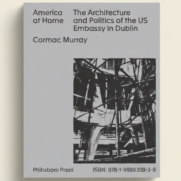 Book cover of 'America at Home: The Architecture and Politics of the US Embassy in Dublin' by Cormac Murray with a black and white photo of an embassy structure.