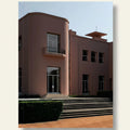 Modern architectural building with curved design and steps leading up to it.