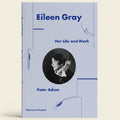 Book cover of 'Eileen Gray: Her Life and Work' by Peter Adam with a portrait of Eileen Gray on a light blue background.