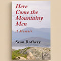 Book cover of 'Here Come the Mountainy Men' by Sean Rothery with a scenic background.