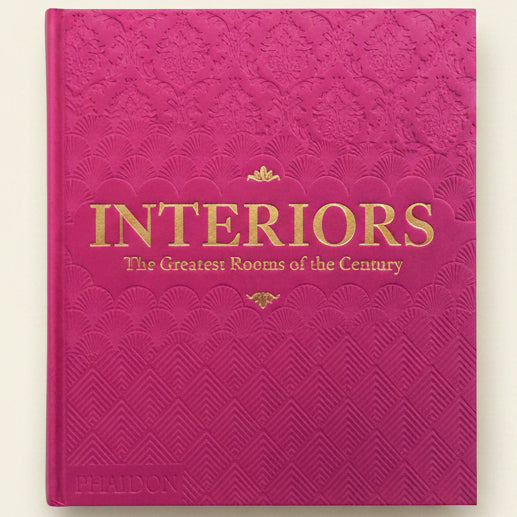Pink book titled 'Interiors: The Greatest Rooms of the Century' with gold text.