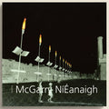 Street scene with torch-lit poles and people in a black and white setting, featuring the text 'McGarry Náéanaigh'.