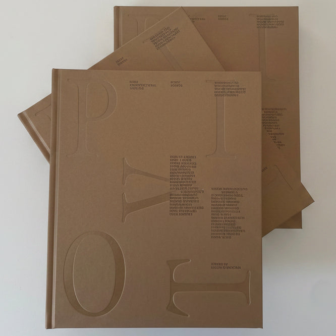 Three minimalist brown paper booklets or catalogs stacked on a light gray surface, featuring large embossed letters and small printed text.
