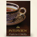 Teacup with saucer on a wooden surface, with 'The Interview' by Patricia O'Reilly.