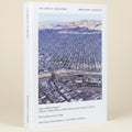 Book cover of 'Two Sides of the Border' with an aerial view of a city and desert landscape.