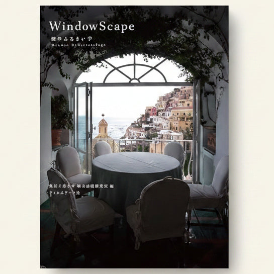 Indoor setting with a large window offering a view of a coastal town, featuring chairs and a table.
