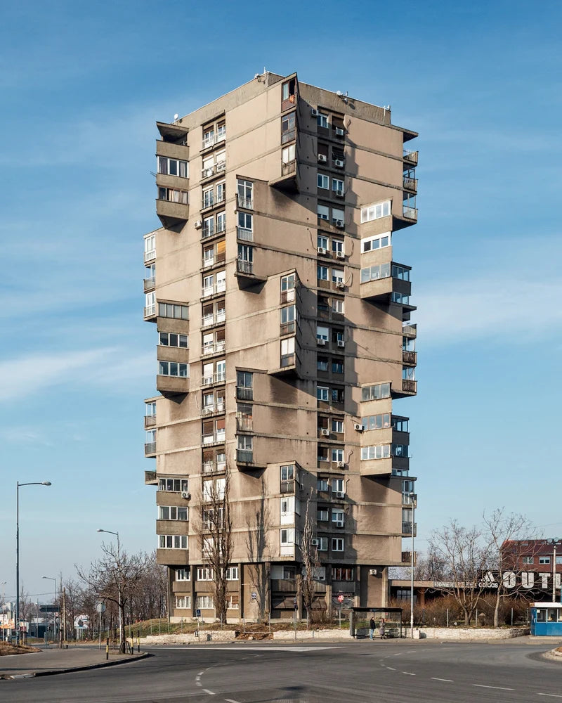 Tall apartment building with a unique architectural design against a blue sky.
